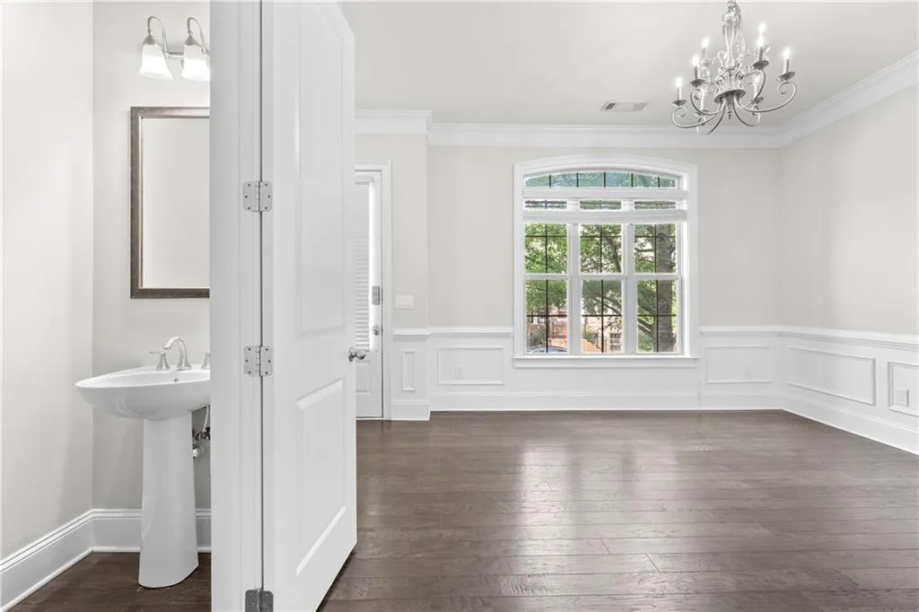 Entrance foyer with dark wood finished floors, a chandelier, ornamental molding, and wainscoting