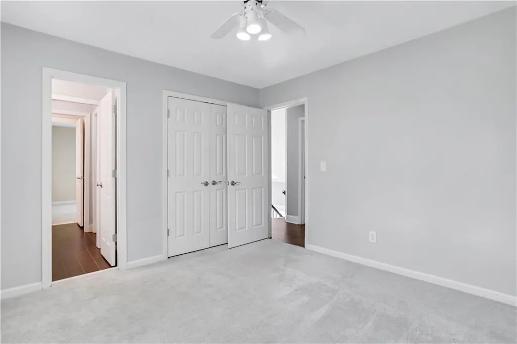 Unfurnished bedroom with a closet, ceiling fan, and dark carpet Unfurnished bedroom with a closet, ceiling fan, and dark carpet