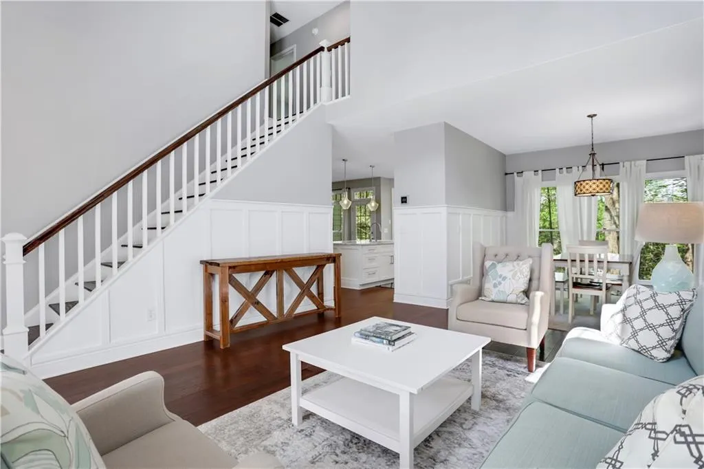 Living room featuring wood-type flooring, a wealth of natural light, and a towering ceiling Living room featuring wood-type flooring, a wealth of natural light, and a towering ceiling