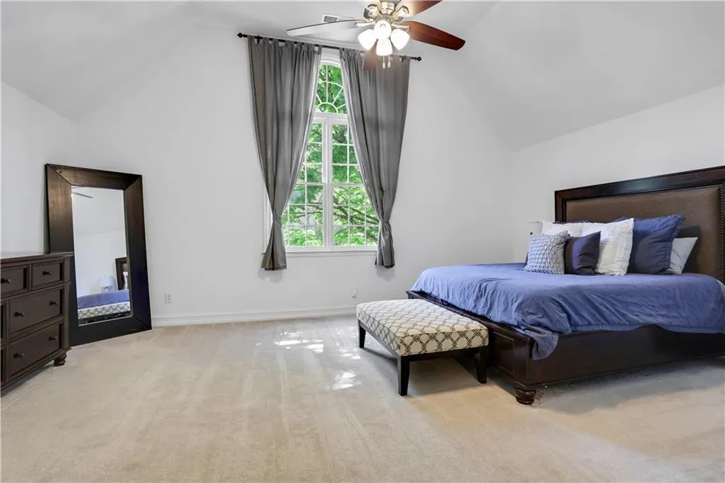 Bedroom with light carpet, ceiling fan, and lofted ceiling Bedroom with light carpet, ceiling fan, and lofted ceiling