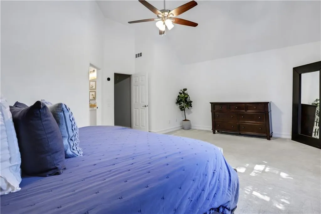 Bedroom with high vaulted ceiling, light carpet, and ceiling fan Bedroom with high vaulted ceiling, light carpet, and ceiling fan