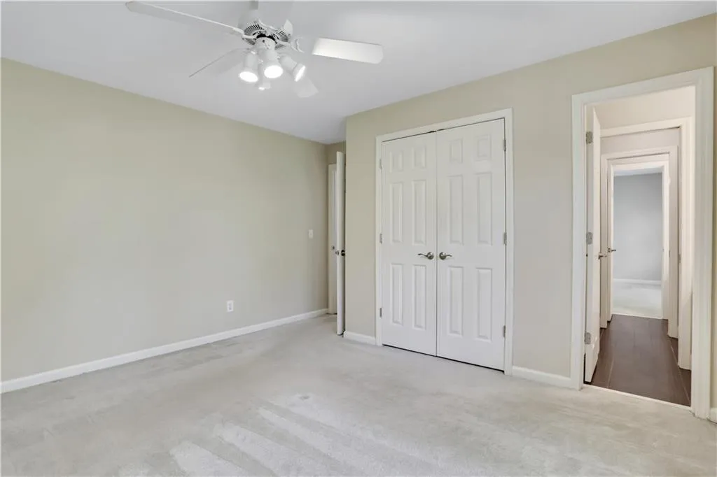 Unfurnished bedroom with light colored carpet, a closet, and ceiling fan Unfurnished bedroom with light colored carpet, a closet, and ceiling fan
