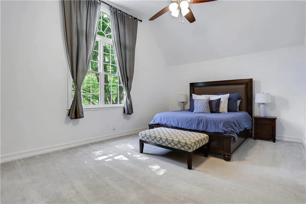 Bedroom featuring light colored carpet, ceiling fan, and lofted ceiling Bedroom featuring light colored carpet, ceiling fan, and lofted ceiling