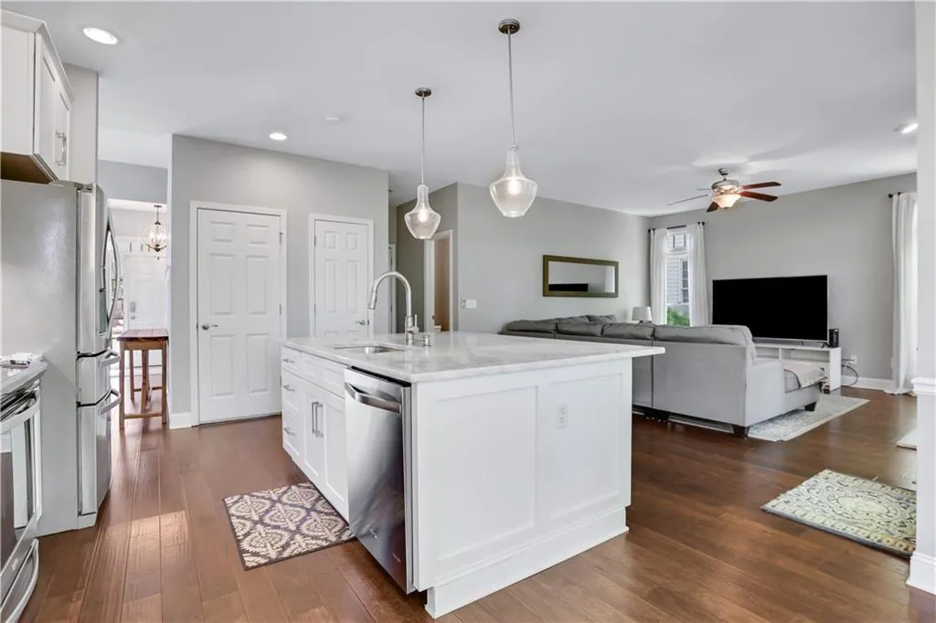 Kitchen featuring decorative light fixtures, appliances with stainless steel finishes, ceiling fan, white cabinets, and sink Kitchen featuring decorative light fixtures, appliances with stainless steel finishes, ceiling fan, white cabinets, and sink