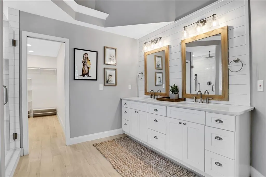 Bathroom with a shower with shower door, double vanity, and hardwood / wood-style floors Bathroom with a shower with shower door, double vanity, and hardwood / wood-style floors