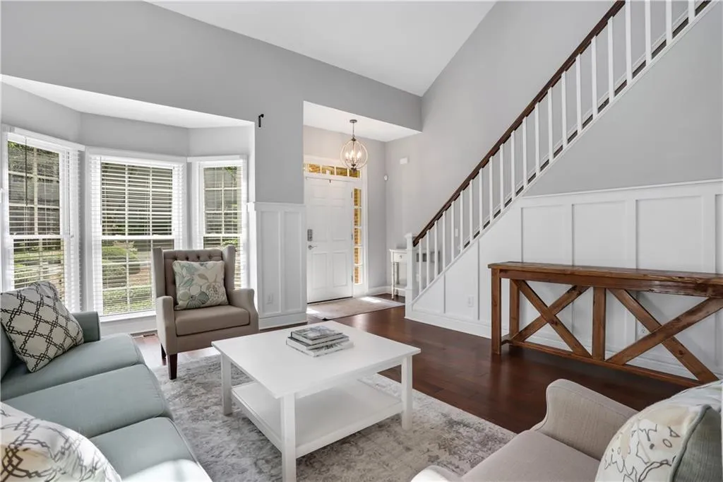 Living room featuring lofted ceiling, dark wood-type flooring, and a notable chandelier Living room featuring lofted ceiling, dark wood-type flooring, and a notable chandelier