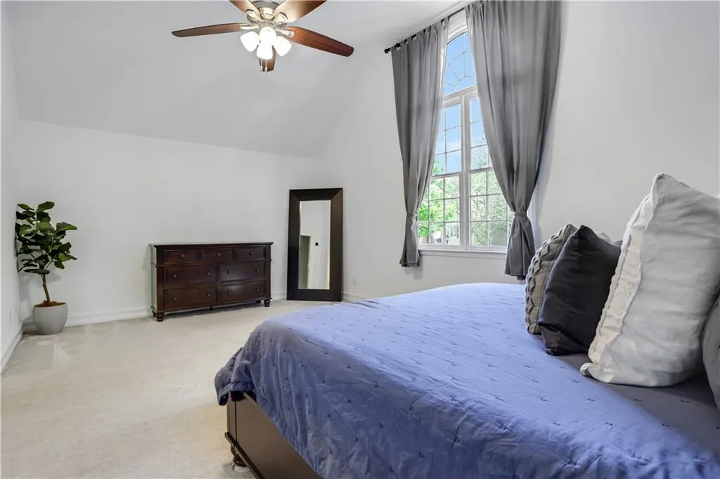 Carpeted bedroom with vaulted ceiling and ceiling fan Carpeted bedroom with vaulted ceiling and ceiling fan