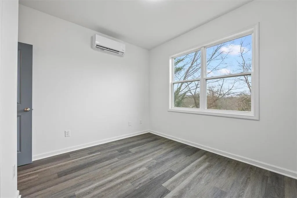 Empty room with dark hardwood / wood-style flooring and a wall mounted AC