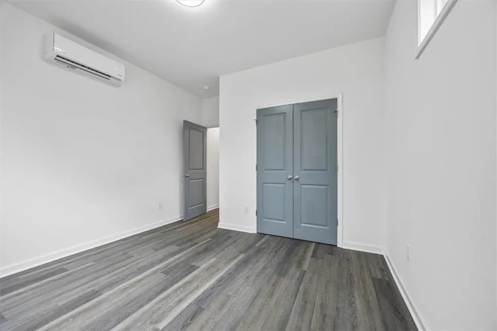 Unfurnished bedroom with a closet, dark hardwood / wood-style floors, and a wall mounted air conditioner