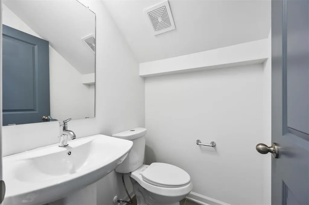 Bathroom with toilet, vaulted ceiling, and sink