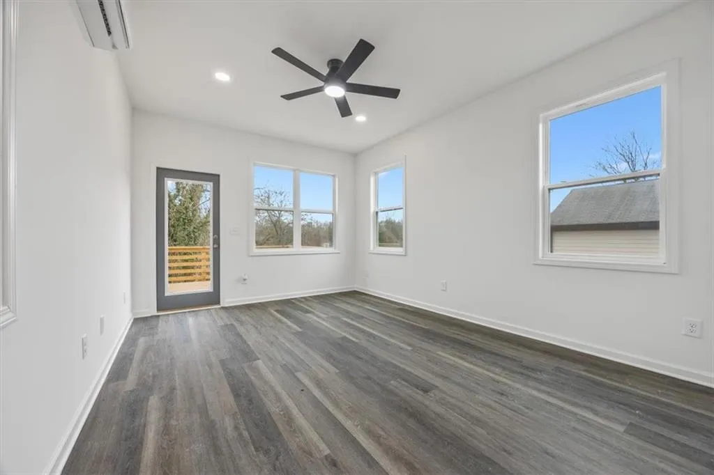 Spare room featuring ceiling fan, dark wood-type flooring, and a wall unit AC