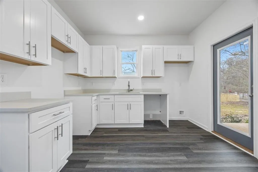 Kitchen with white cabinets, dark wood-type flooring, and sink