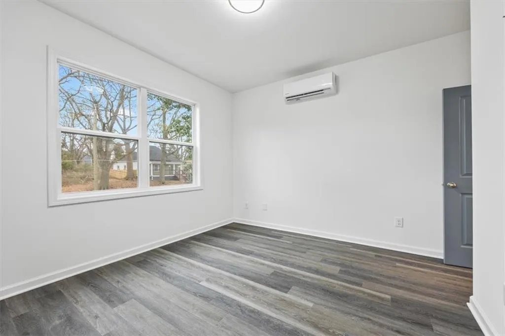 Unfurnished room featuring dark hardwood / wood-style floors and a wall mounted air conditioner
