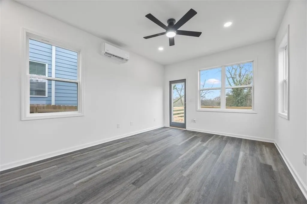 Spare room featuring ceiling fan, dark hardwood / wood-style flooring, and a wall unit AC