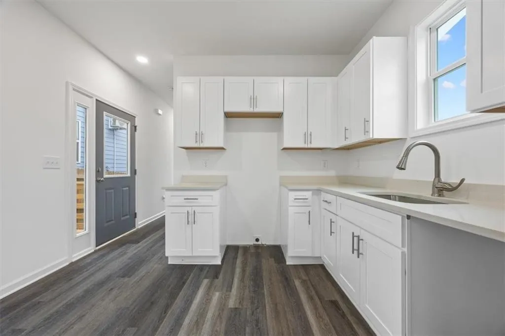 Kitchen with dark wood-type flooring, sink, and white cabinetry