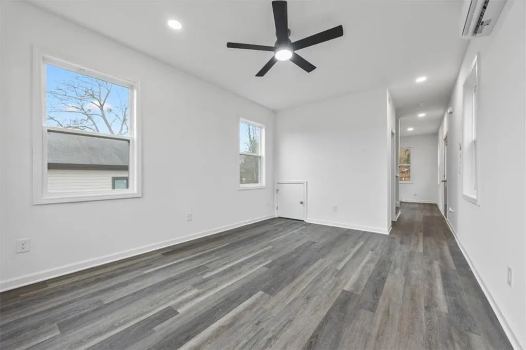 Empty room with ceiling fan, dark hardwood / wood-style floors, and a wall mounted AC