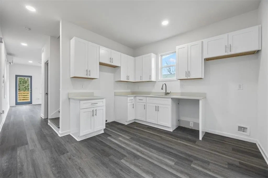 Kitchen with dark hardwood / wood-style flooring, sink, and white cabinetry