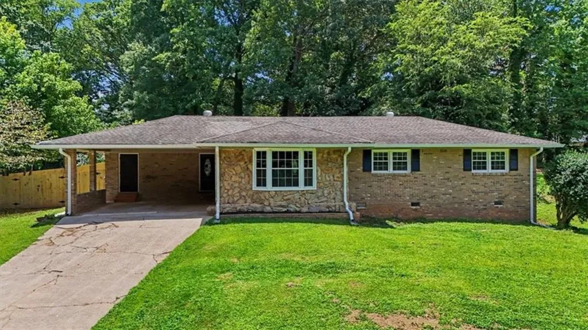 Ranch-style exterior featuring a stone and brick facade, a covered carport, and a prominent front door