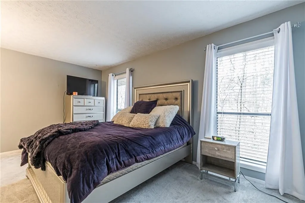 Bedroom with light colored carpet and a textured ceiling