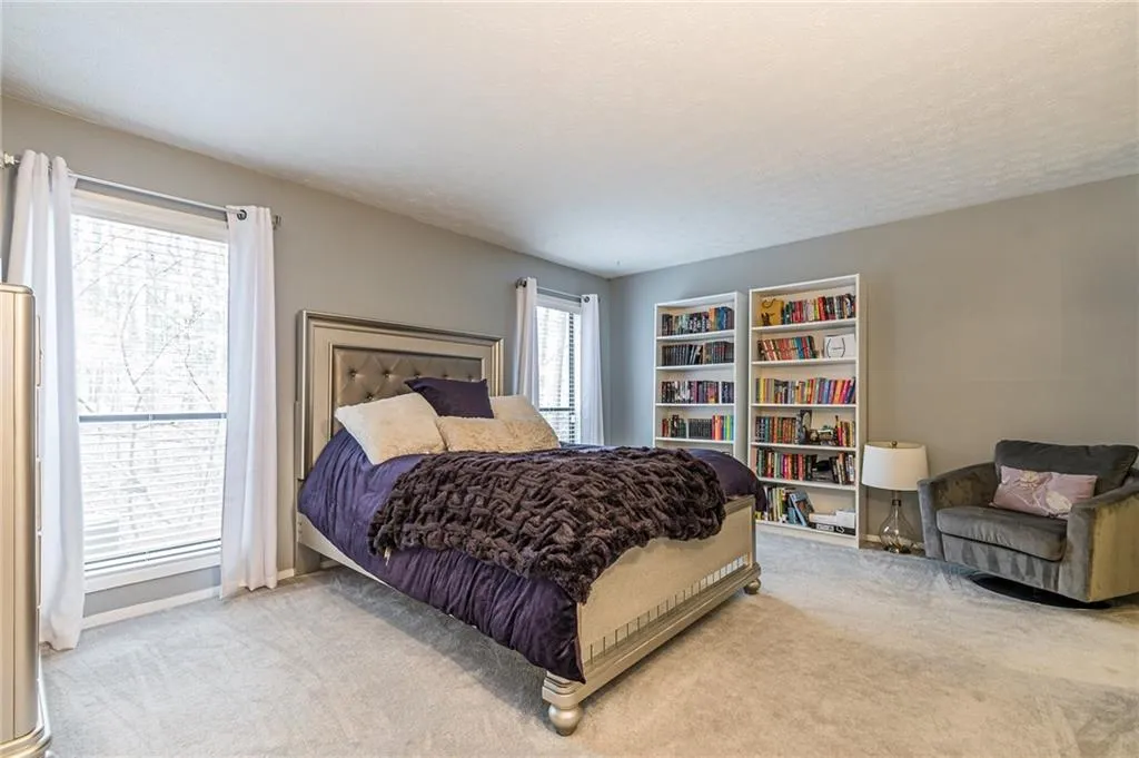 Bedroom with light colored carpet and multiple windows