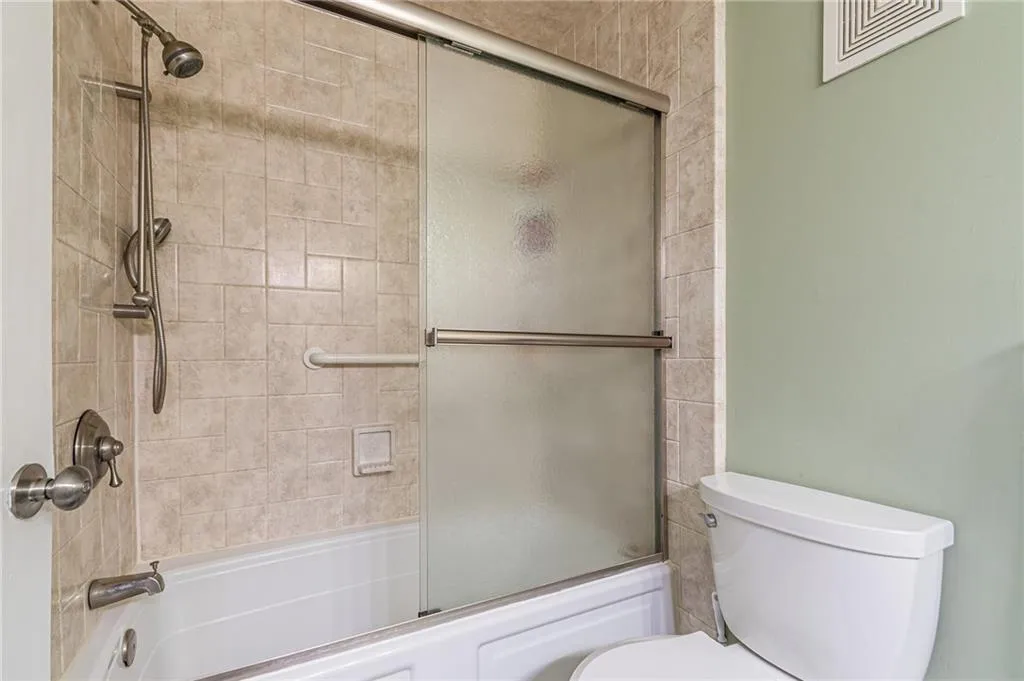 Bathroom with toilet and shower / bath combination with glass door