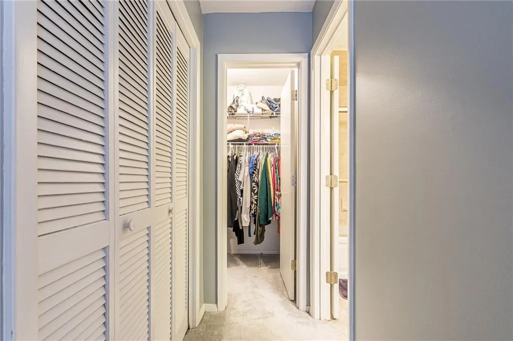 Corridor featuring light colored carpet