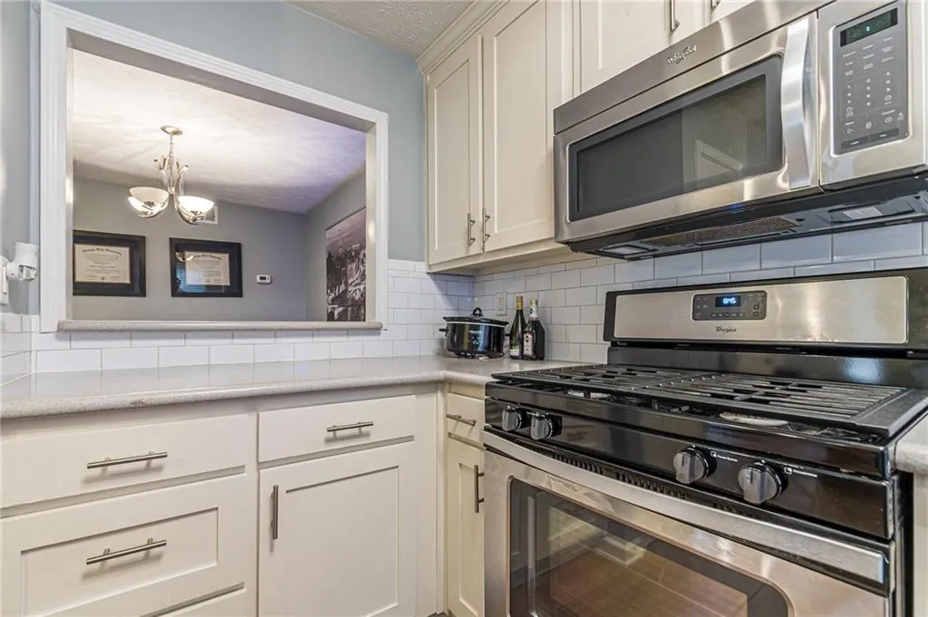 Kitchen with an inviting chandelier, stainless steel appliances, decorative light fixtures, and backsplash