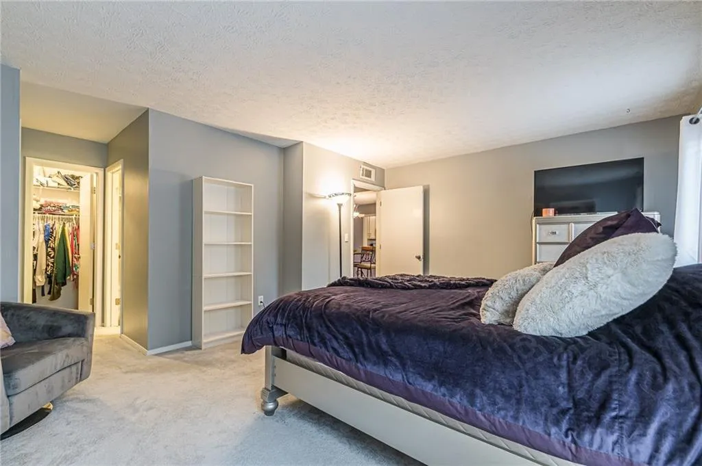 Carpeted bedroom with a textured ceiling, a closet, and a walk in closet