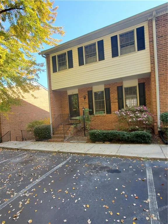 Colonial home with uncovered parking, brick siding, and covered porch