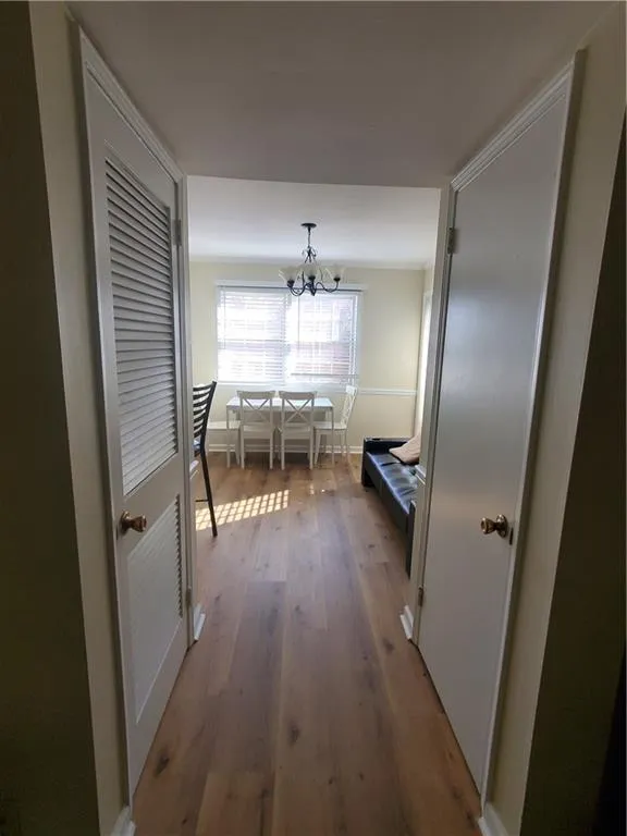Hall featuring dark wood-style floors and a chandelier