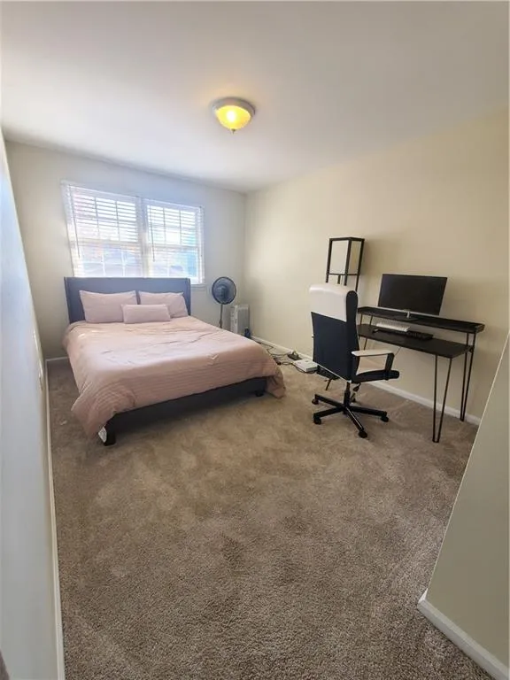 Carpeted bedroom with baseboards and an office area