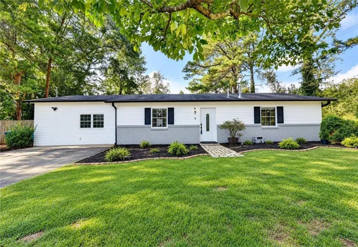 White siding exterior with a grey brick accent, black roof, black shutters, and a white front door with a glass insert