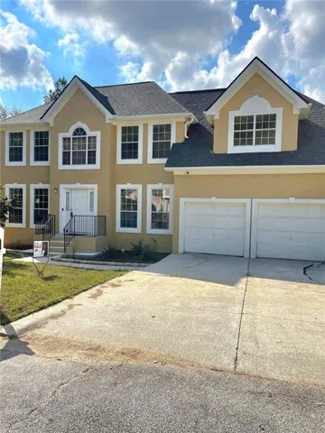 View of front facade with roof with shingles, driveway, stucco siding, and an attached garage