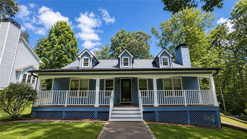 Blue siding residence featuring a covered front porch, white balustrade, and three dormer windows