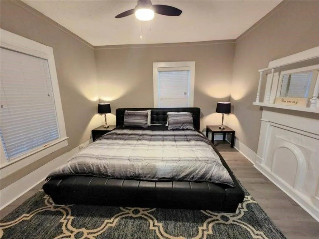Bedroom featuring a ceiling fan, baseboards, ornamental molding, and wood finished floors