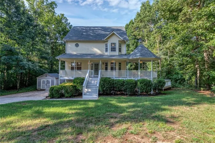 Two-story residential structure with a covered front porch featuring a gazebo, elevated deck, and a detached shed