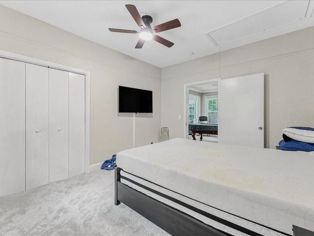 Bedroom featuring attic access, carpet flooring, and ceiling fan