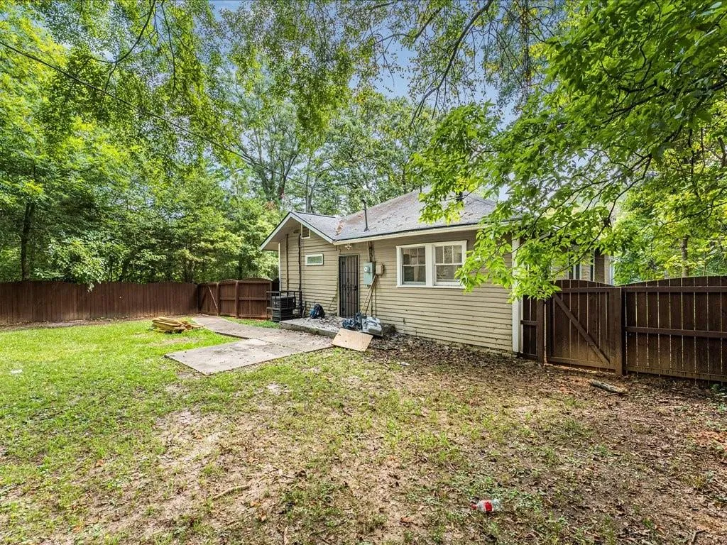 Rear view of house with a gate, a fenced backyard, a patio, and view of scattered trees