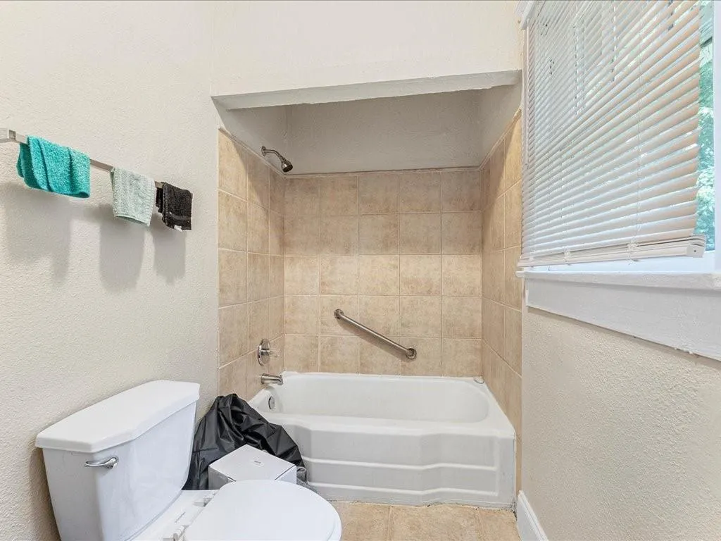 Bathroom featuring a textured wall, tub / shower combination, and tile patterned flooring