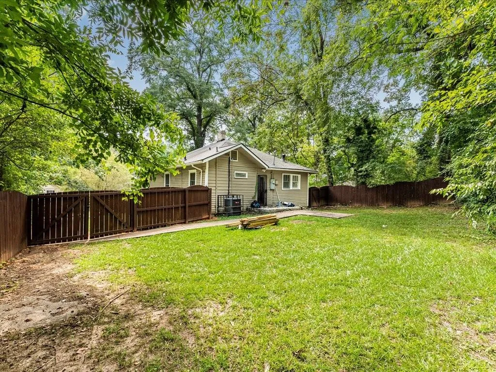 Fenced backyard featuring a patio and view of scattered trees