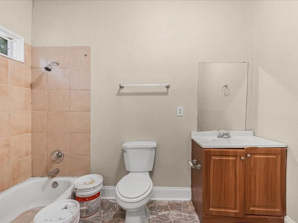 Full bath with bathing tub / shower combination, vanity, and a textured wall