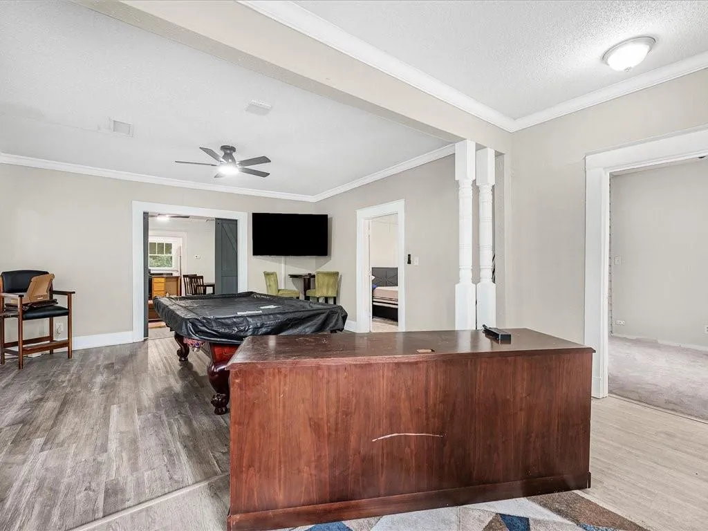 Recreation room featuring pool table, ornamental molding, ceiling fan, light wood finished floors, and a textured ceiling