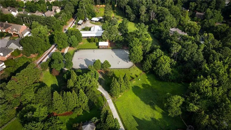 Expansive equestrian property featuring a large riding arena, multiple outbuildings, and extensive wooded grounds