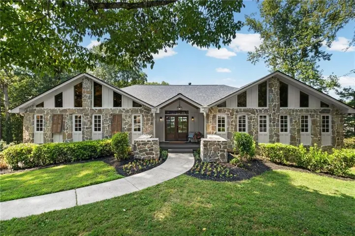 Stone facade residence with a gabled roofline, multiple pane windows, and a paved walkway leading to the front entry