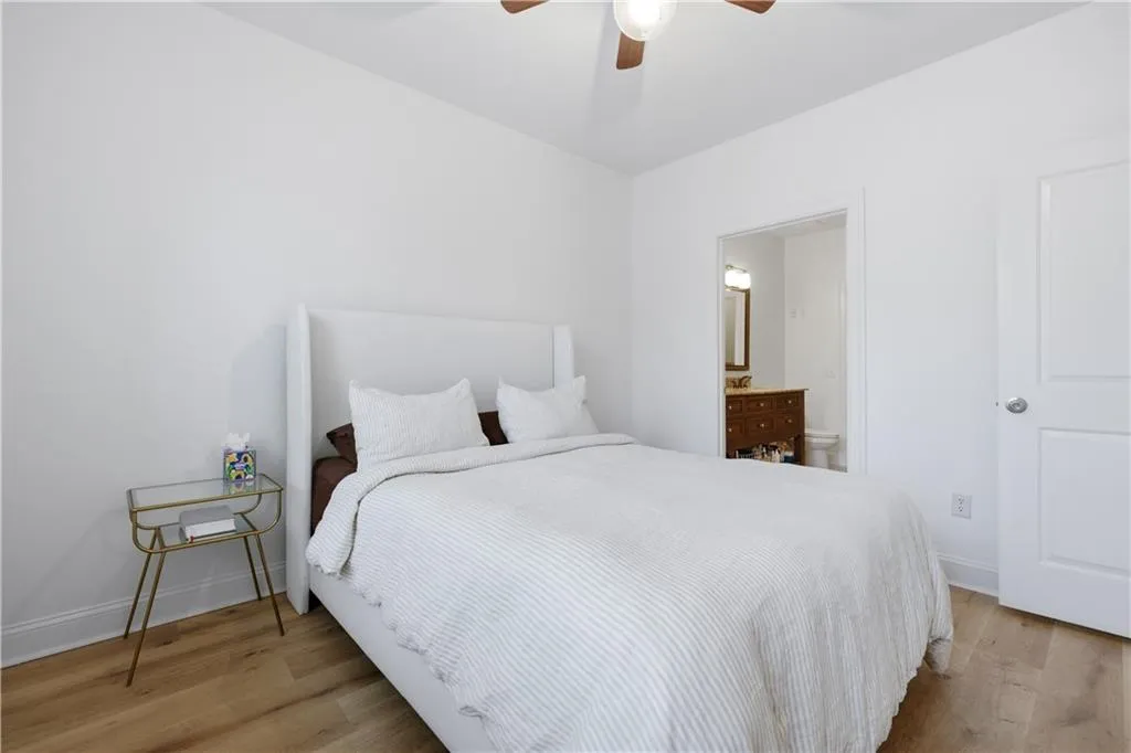 Bedroom with light wood-style floors, connected bathroom, and ceiling fan
