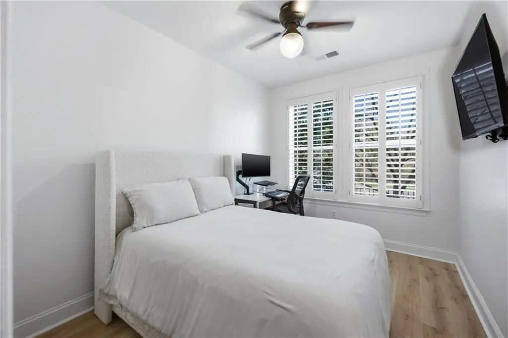 Bedroom with a desk, light wood-style floors, and ceiling fan