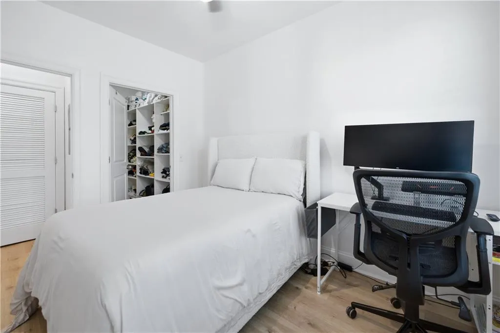 Bedroom with light wood-type flooring, a walk in closet, and an office area