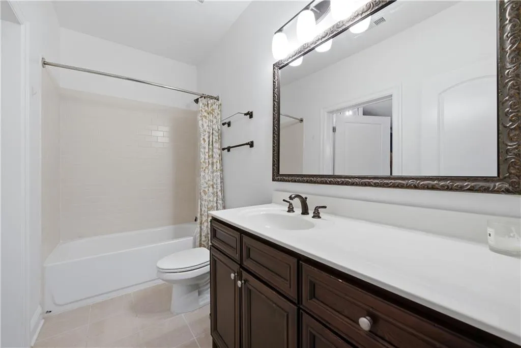 Bathroom featuring vanity, shower / bathtub combination with curtain, and light tile patterned floors