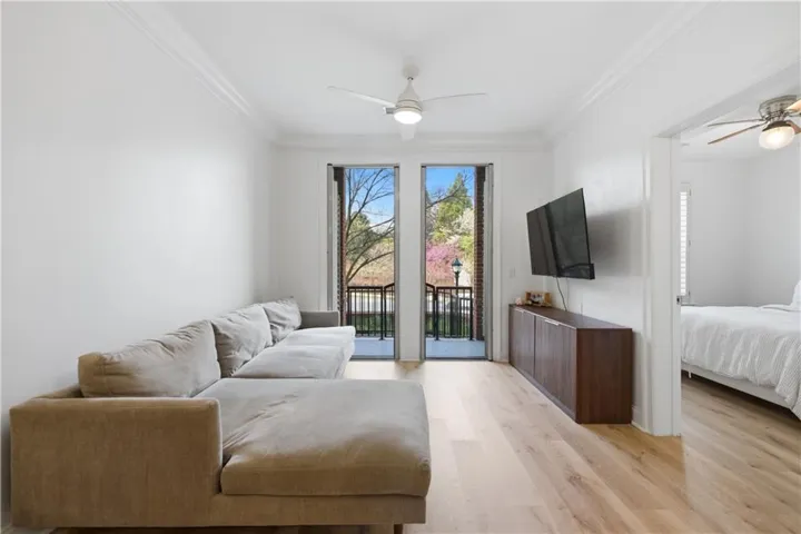 Living area with a ceiling fan, light wood-style flooring, and ornamental molding