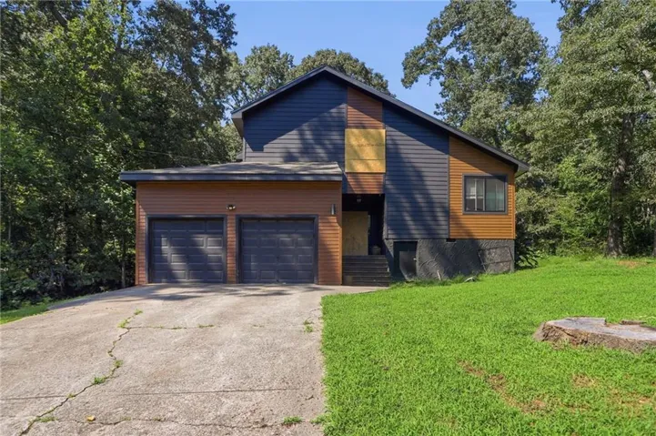 Multi-level exterior with dark gray and wood-tone siding, featuring a two-car garage with dark gray doors